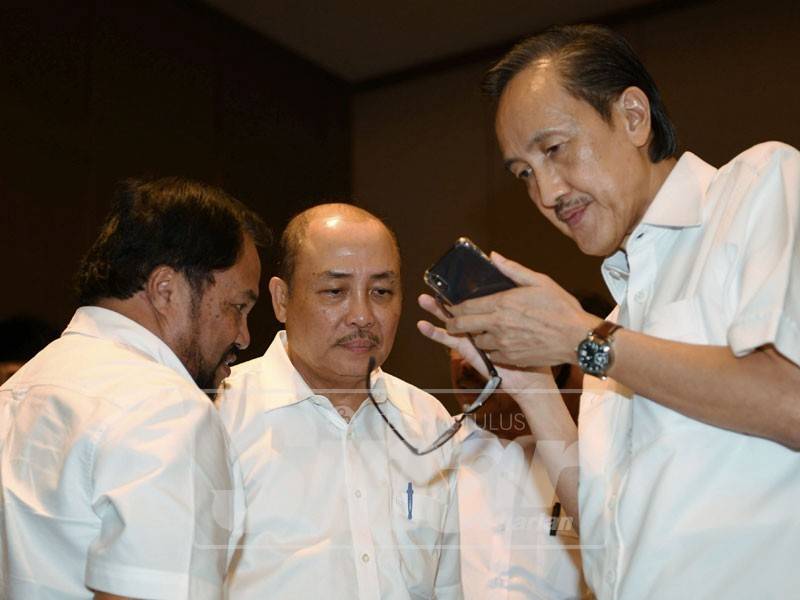 Masidi membaca dengan teliti mesej yang diterima beliau daripada pemimpin Umno Pusat selepasHajiji (tengah) mengumumkan sembilan ahli Dun dan lima anggota Parlimen daripada Umno keluar dari parti itu ketika sidang akhbar hari ini. - Foto Bernama