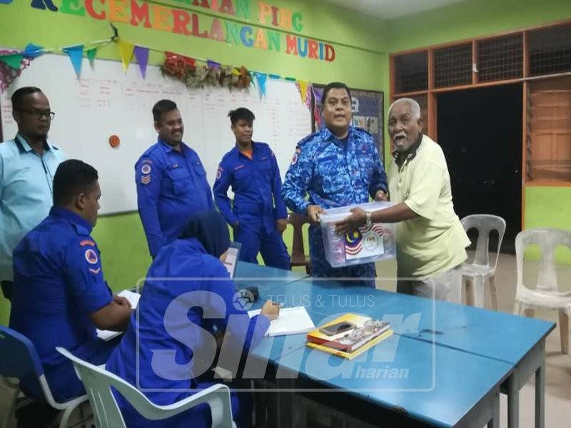 Mohd Fazly menyerahkan kit makanan kepada mangsa banjir di SK Changkat Jong.