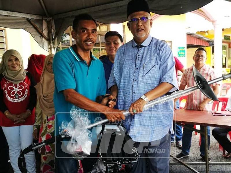 Mahfuz (tengah) menyerahkan sumbangan mesin pemotong rumput kepada penerima Dun Bukit Lada.