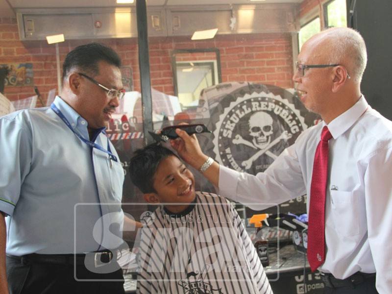 Sazally (kiri) ketika melihat kanak-kanak yang mengambil peluang gunting rambut yang ditawar secara percuma.