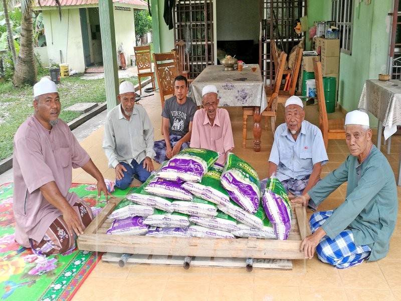 Ustaz Din (kiri) menerima beras fidyah daripada penduduk untuk diagih kepada golongan asnaf.