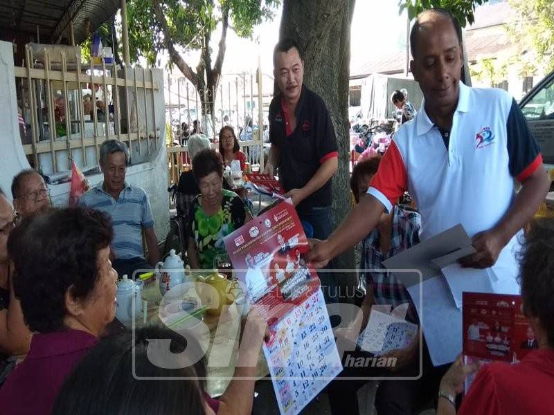 Kula Segaran mengedarkan kalendar kepada orang ramai yang berada di sekitar Pasar Kampung Tawas.