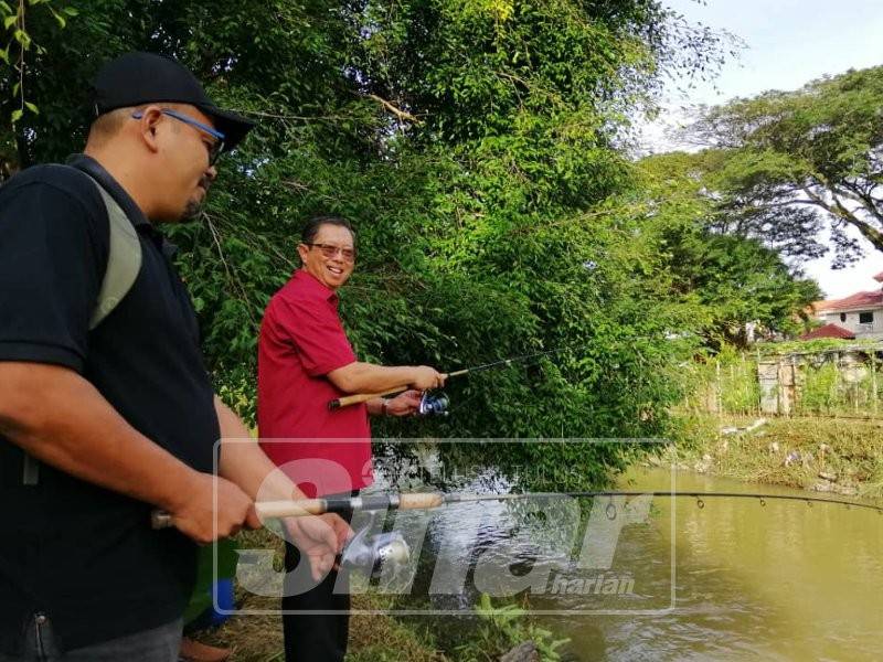 Mohammad Nizar (kanan) menyempurnakan gimik pertandingan memancing Sungai Pinji, hari ini.