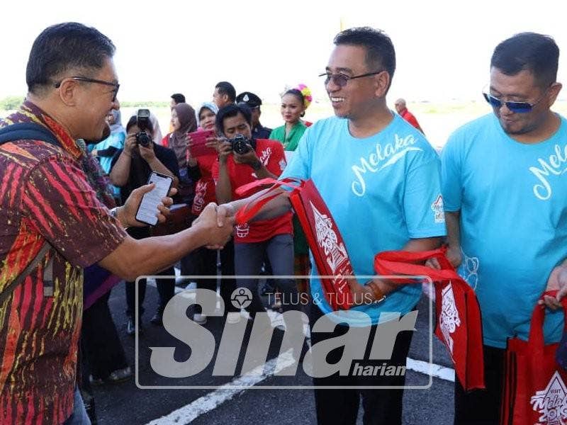 Adly (dua,kanan) dan Muhammad Jailani (kanan) ketika menyampaikan cenderahati kepada pelancong pada majlis sambutan kedatangan pelancong di LTAM, Batu Berendam, di sini, hari ini.