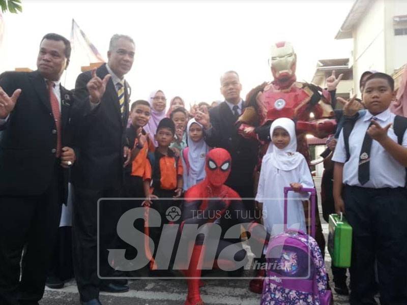 Suhaidi (kiri) dan Idris (dua kiri) bergambar bersama murid Tahun 1 yang teruja disambut maskot Iron Man dan Spiderman pada hari pertama sesi persekolahan baharu di Hipersis semalam.