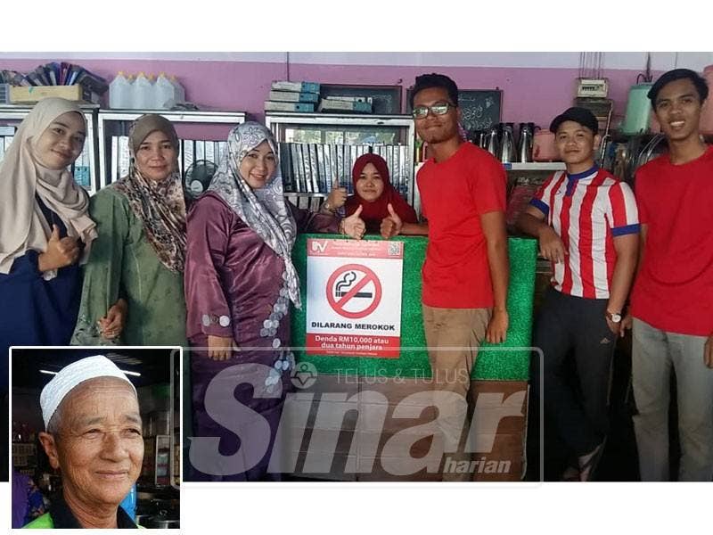 Noor Awani (tiga, kiri) menampal papan tanda amaran larangan merokok di kedainya.