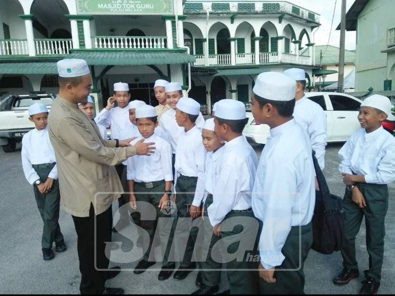 Nik Hamdi (kiri) beramah mesra bersama pelajar baru di SMUDA, pagi semalam.