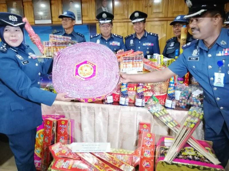 Azimah (kiri) menunjukkan sebahagian mercun dan bunga api yang berjaya dirampas JKDM Perak, 27 Disember lalu.