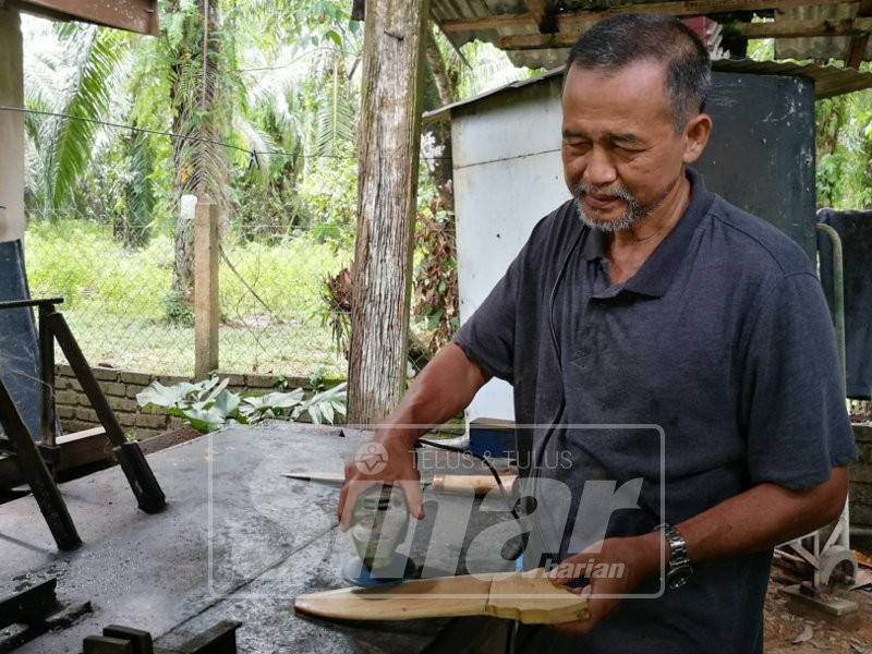 Mohd Remli tekun siapkan sarung pisau.