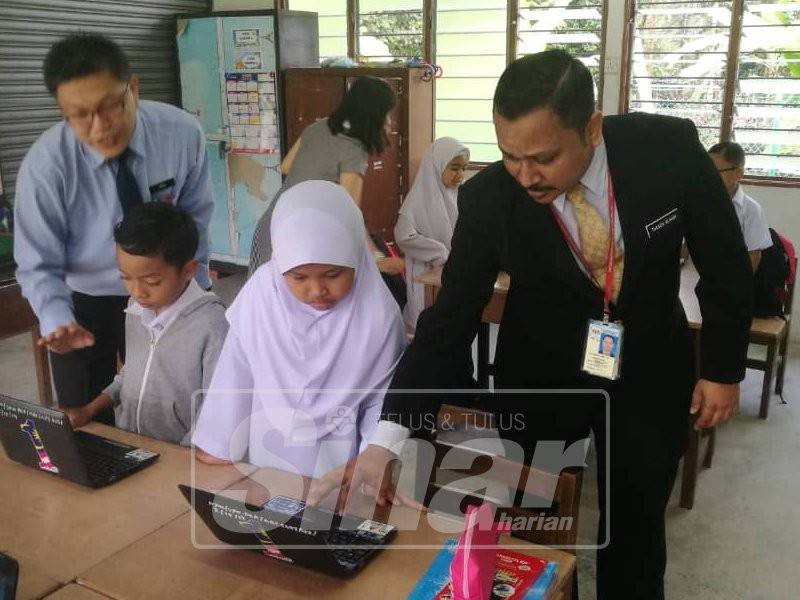 Theng Guan (kiri) dan Thesok Kumar (kanan) meninjau pelajar kelas bercantum Darjah Dua dan Tiga SJKC Yuk Chuen mengikuti sistem pembelajaran dan pengajaran di sekolah itu hari ini.