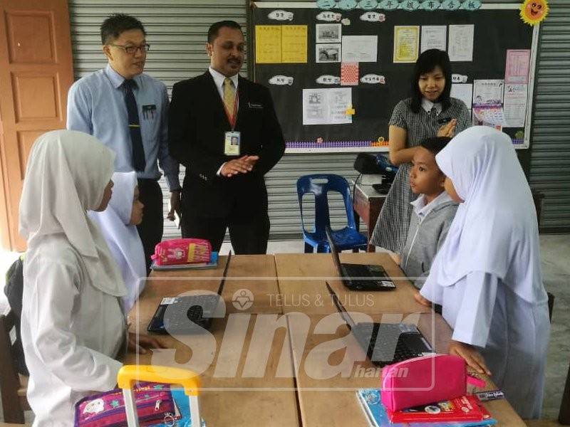 Theng Guan (belakang, kiri) dan Thesok Kumar (belakang, tengah) menyantuni beberapa pelajar SJKC Yuk Chuen sambil diiringi guru kelas mereka.