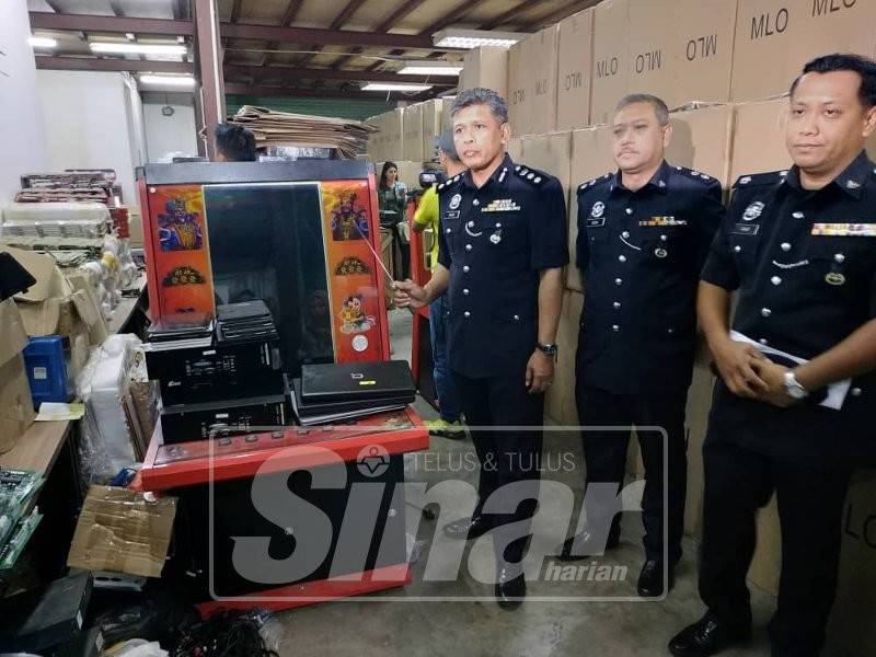Ismadi (kiri) menunjukkan mesin simulator perjudian yang disembunyikan di premis kilang ini.