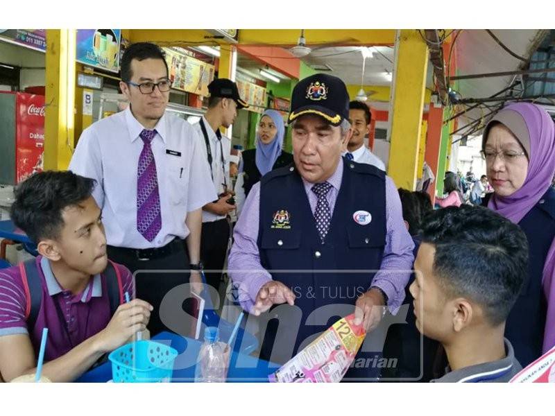 Dr Mohd mengedarkan risalah larangan merokok di premis makan kepada dua remaja di sebuah medan selera di bandar raya ini.