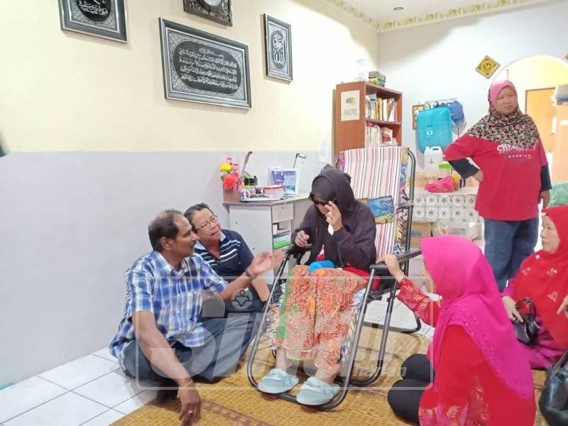 Noraqilah (duduk di kerusi) ketika diziarahi Manickam (kiri).