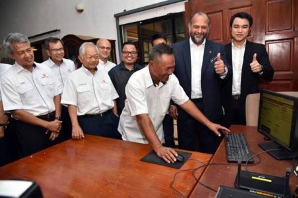 Gobind dan Moggie melihat Pengerusi Majlis Pengurusan Kampung Kampung (MPKK) juga generasi kedua peneroka Felda, Redwan Sentul, 58, melayari internet di rumahnya.