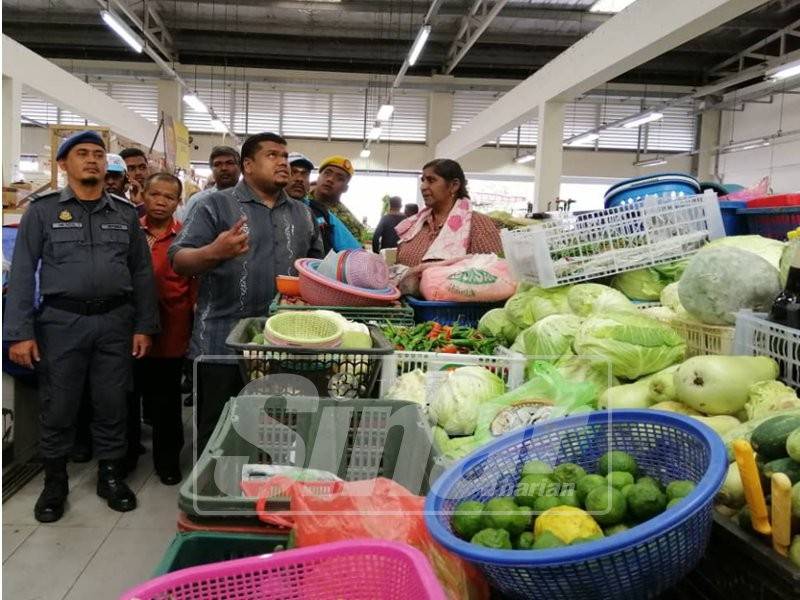 Muhamad Arafat (hadapan, tengah) mendengar aduan disuarakan peniaga di Pasar Tanjung Rambutan.
