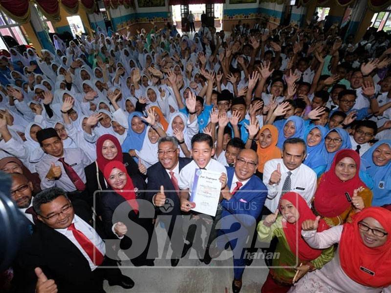 Muhammad Syukur (tengah) menerima Anugerah Pelajar Unggul dan diraikan sempena Majlis Pelancaran Guru Penyayang SMK Padang Midin, hari ini.