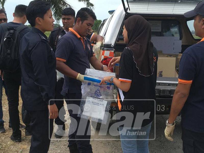 Anggota forensik memeriksa bungkusan kain putih didakwa mengandungi janin bayi yang ditemui tertanam di sebuah kawasan sawah padi di Bukit Rambai, pagi tadi.