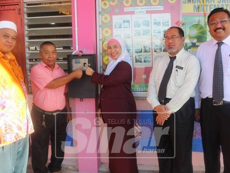 Nur'asikin (tiga, kanan) bersama Mohd Subri (kiri) menunjukkan salah satu mesin pengimbas cap jari di sekolah mereka.