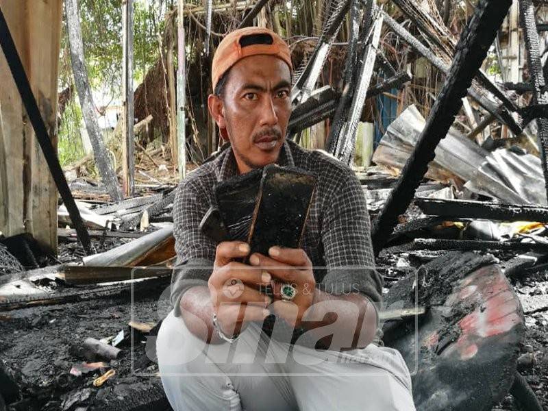 Roslee menunjukkan tiga telefon bimbitnya yang hangus terbakar.