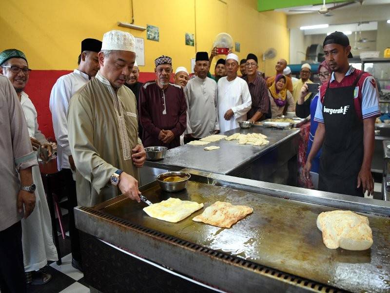 Sultan Pahang, Sultan Abdullah Ahmad Shah menunjukkan bakat memasak roti canai ketika bersarapan bersama rakyat di sebuah restoran selepas menunaikan solat Subuh di Masjid Ash Shafie, Kotasas, Kuantan. - Foto Bernama