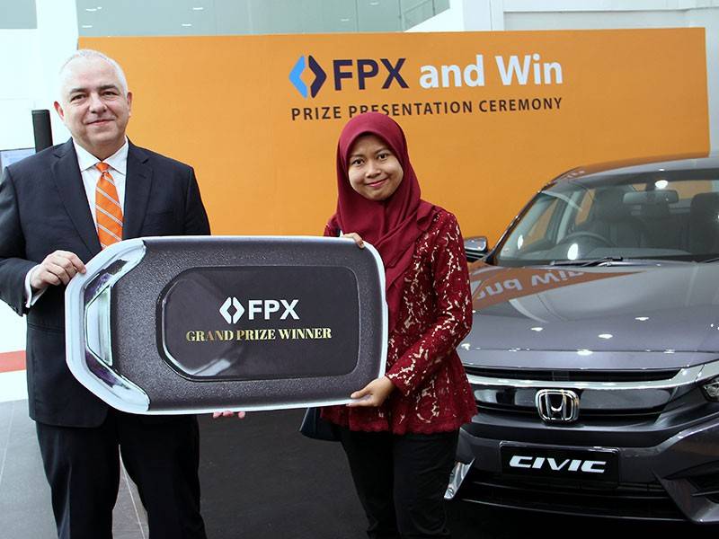 Ketua Pegawai Eksekutif Kumpulan Payments Network Malaysia Sdn Bhd (PayNet) Peter Schiesser menyampaikan hadiah kepada pemenang utama peraduan 'FPX and Win! ' Nurul Fatin Mohd Zulkafli dalam majlis tersebut. - Foto Bernama