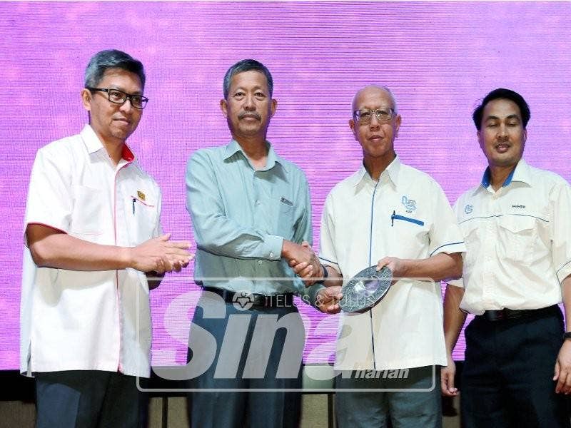 Aziz (dua, kanan) menyampaikan cenderahati kepada tetamu sambil diperhatikan Jamal (kiri)