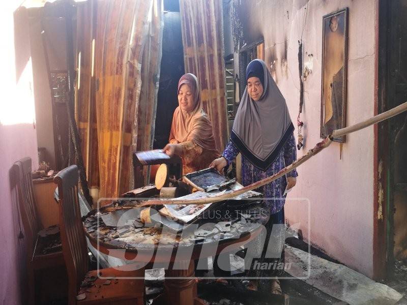 Che Normah (kanan) dan kakaknya,Jamilah Darus melihat kesan kebakaran di rumahnya.