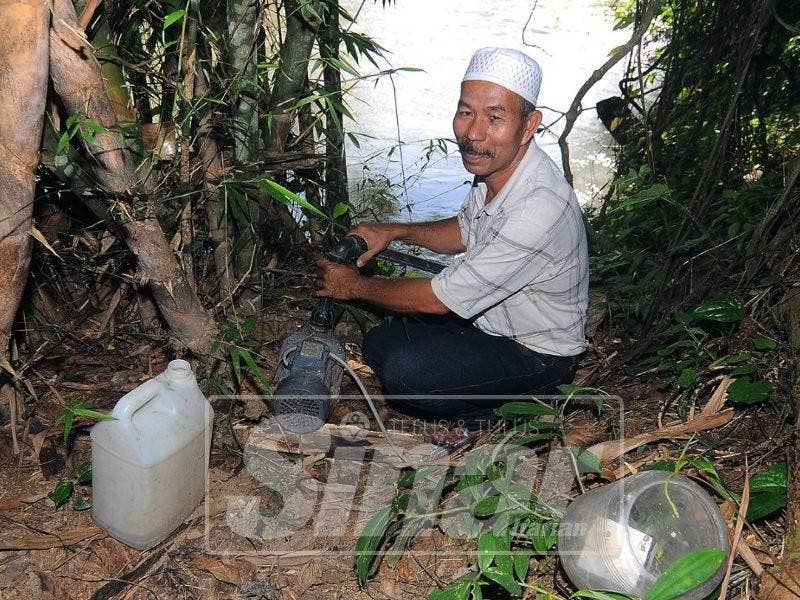 Zolkefly menunjukkan pam air yang dibeli dan dipasang sendiri untuk menyedut air sungai berhampiran. Foto: SINAR HARIAN oleh SHARIFUDIN ABDUl RAHIM