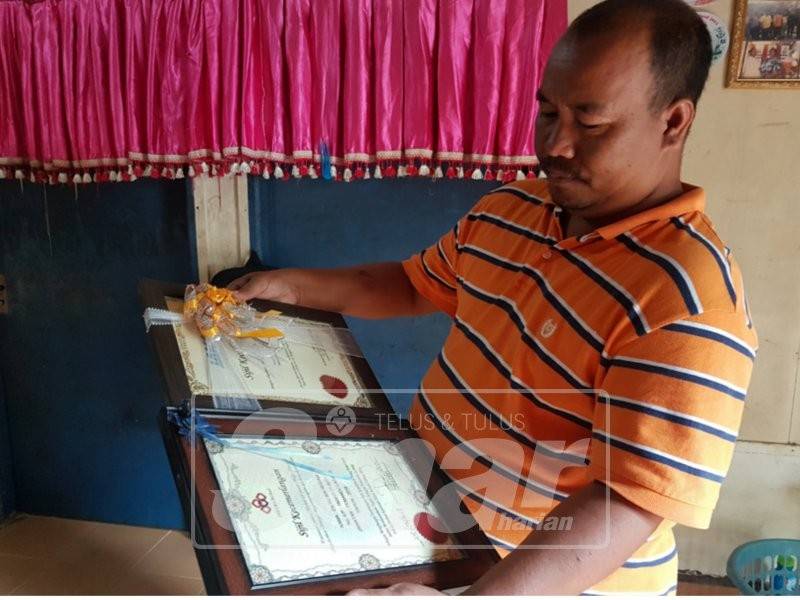 Yu meneliti sijil khidmat cemerlang yang pernah diperolehnya sejak menggalas tugas sebagai mandur ladang di bawah Felcra lima tahun lalu.