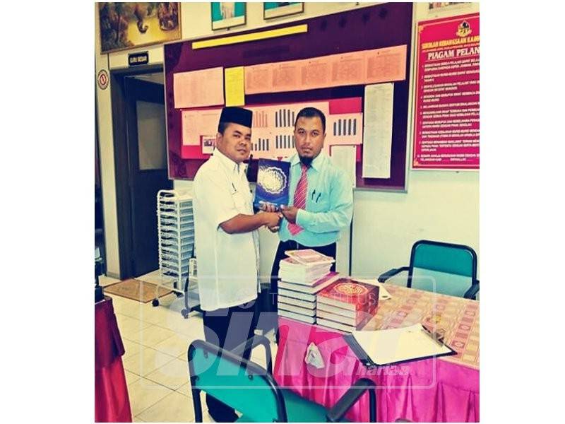 Mohd Nazry (kiri) menyerahkan sumbangan al-Quran kepada kepada wakil pihak sekolah.