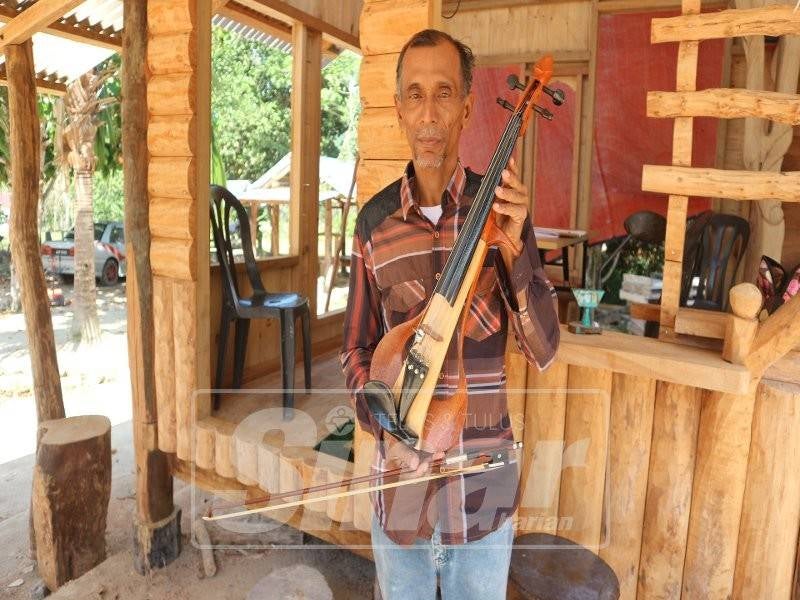 Rusdin menunjukkan biola yang diciptanya dengan menggunakan beberapa jenis kayu.