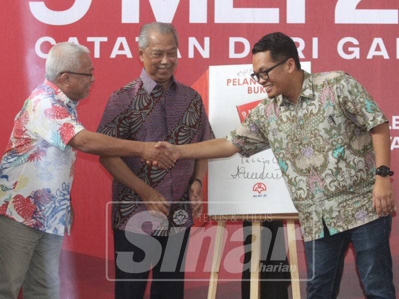 Nik Nazmi (kanan) bersalaman dengan Hussamuddin selepas melancarkan bukunya.