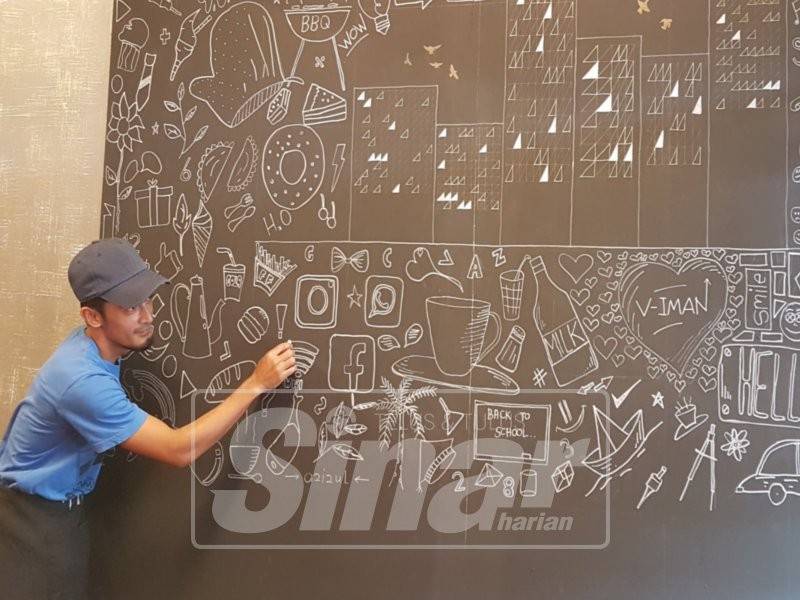 Bakat yang dimiliki membolehkan Mohd Azizul melukis sendiri karya seni atas papan hitam di dalam kafenya.