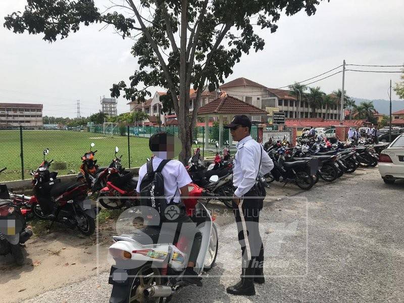 Salah seorang pelajar ditahan kerana tidak memakai topi keledar.