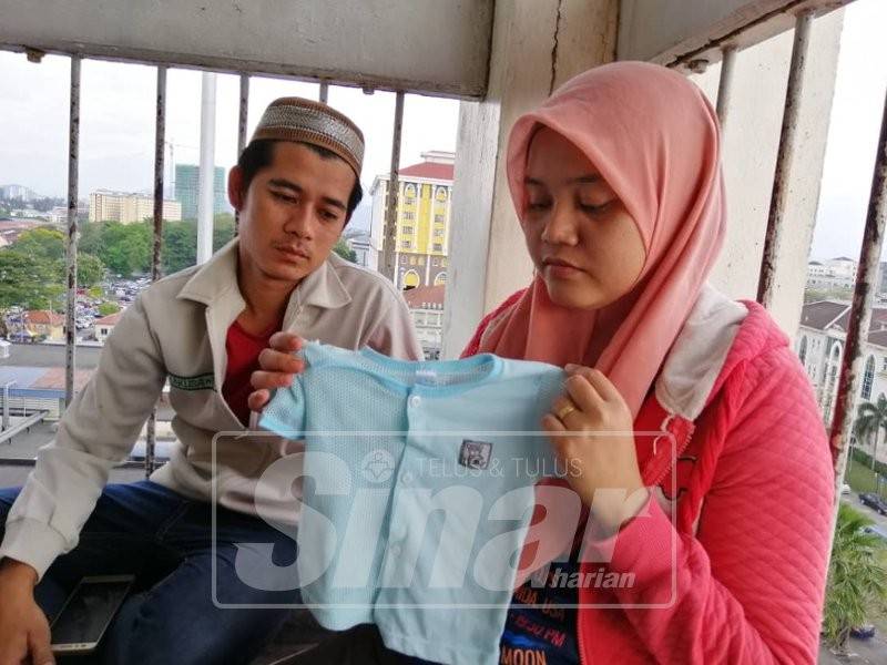 Nur Aziemah dan suami, Muhammd Nizar Ismail, 30, menunjukkan baju terakhir yang dipakai Muhammad Firas.