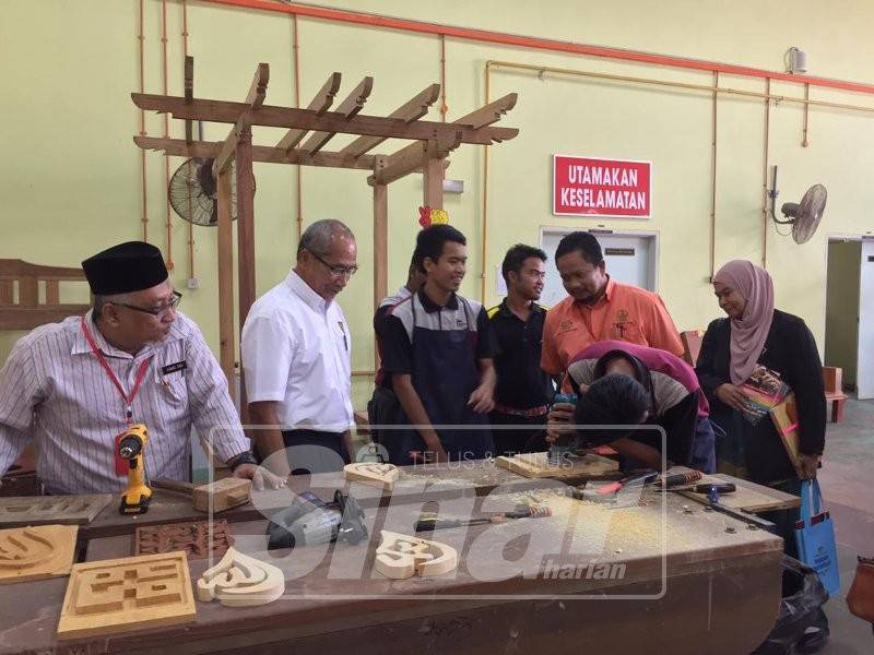 Zainor (dua kiri) melihat pelajar sijil khas Kolej Komuniti Gerik melakukan kerja-kerja ukiran.