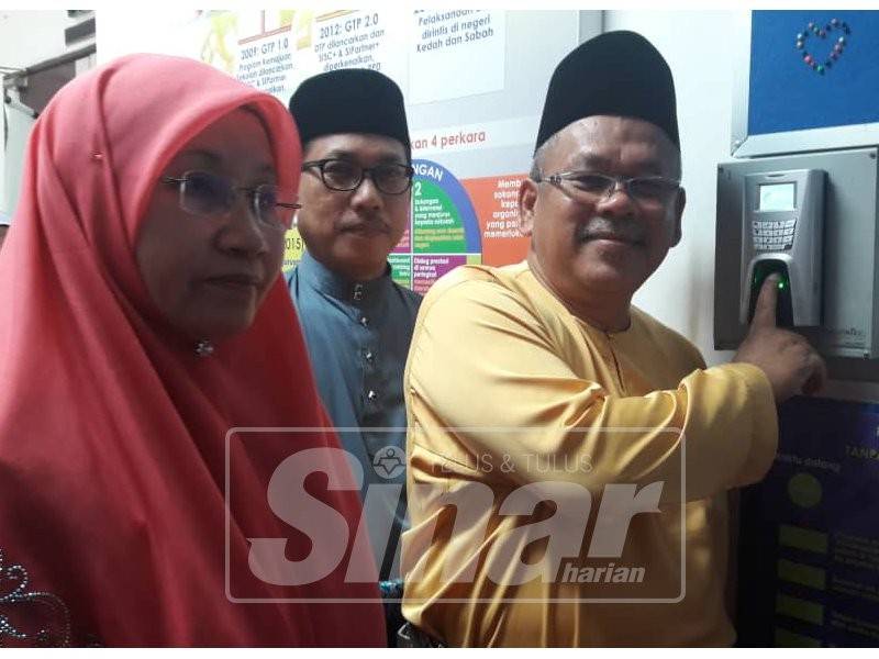 Shaharudin (kanan) mengetik sambil ditemani isterinya, Tursinah (kiri) dan diperhatikan Azman (tengah)