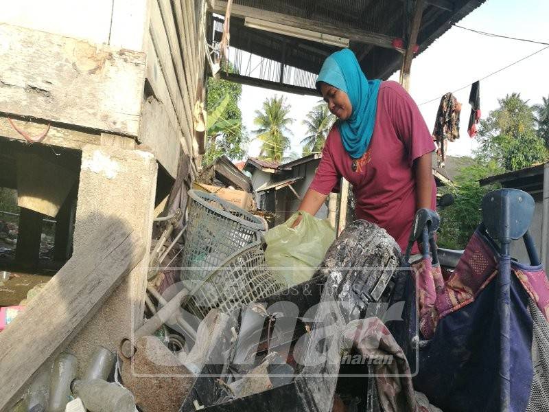 Nor Azizah memeriksa barang-barang terbuang yang dikutip dari tong sampah untuk dijual semula.
