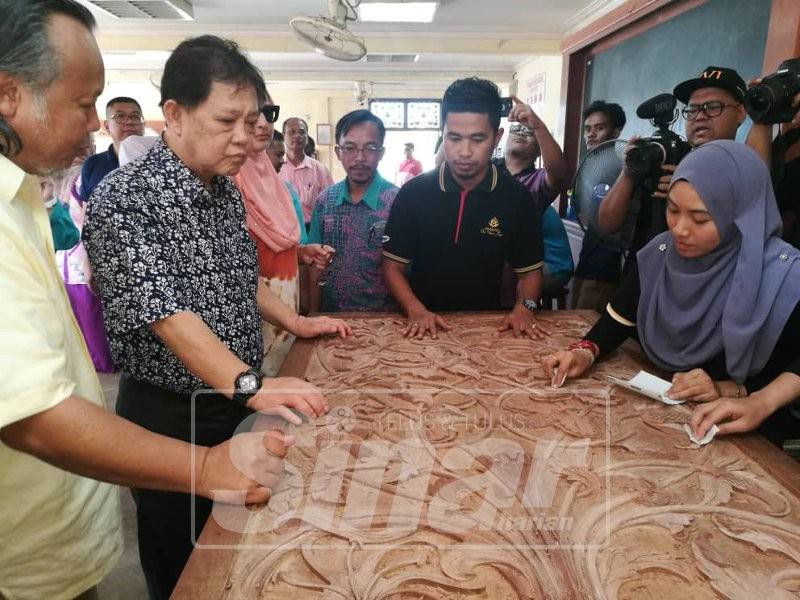 Mohamaddin (dua, kiri) melihat pelatih Desa Ukiran Kayu Besut menghasilkan ukiran kayu di pusat latihan tersebut di Kampung Raja, petang tadi.
