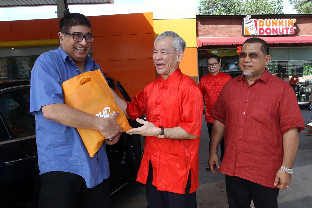 Tan Kim Thiam menyerahkan beg cenderahati kepada pelanggan bertuah yang berkunjung di stesen BHPetrol KL-Karak Arah Timur ketika acara berlangsung.
