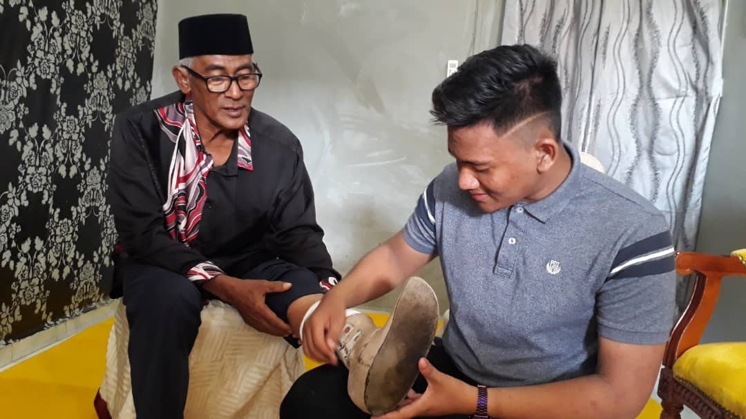 Anak Jasni, Putera Danial, 19, menunjukkan kaki palsu lama yang tidak sesuai lagi dipakai oleh bapanya.