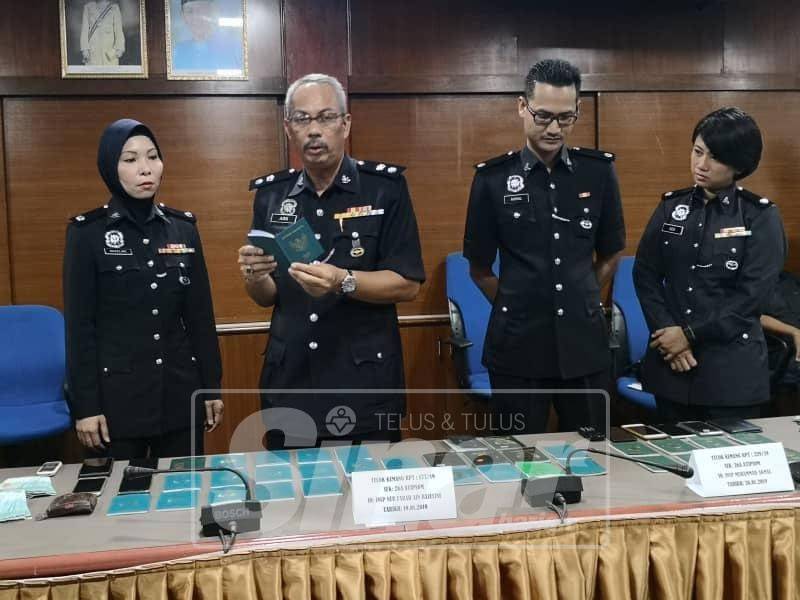 Aidi Sham (dua, kiri) menunjukkan pasport warga asing yang dirampas.