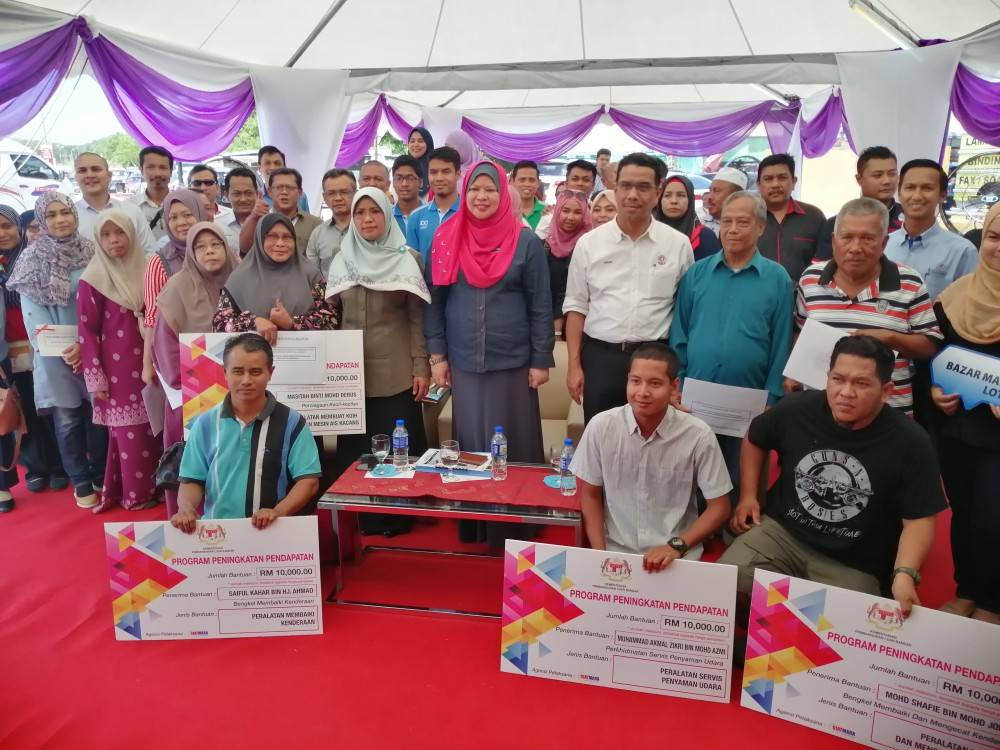 Rina bergambar bersama penerima bantuan sewaktu lawatan kerja ke Bazar Mara, hari ini. 