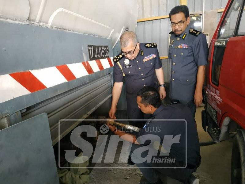 
Rosli (tengah) melihat hos paip yang digunakan sindiket memindahkan gas dari tong ke tangki silinder.
