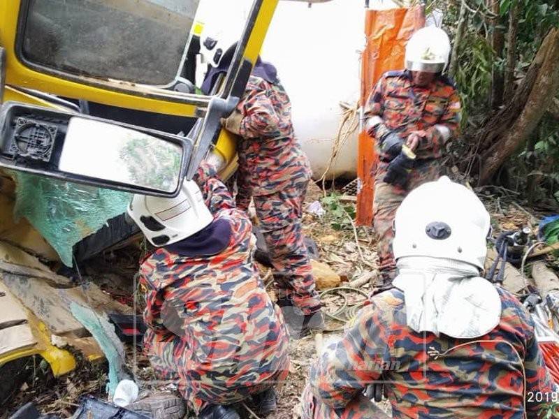 Anggota bomba menjalankan operasi mengeluarkan mayat mangsa yang tersepit dalam kenderaan itu, hari ini. - Foto: JBPM Perak