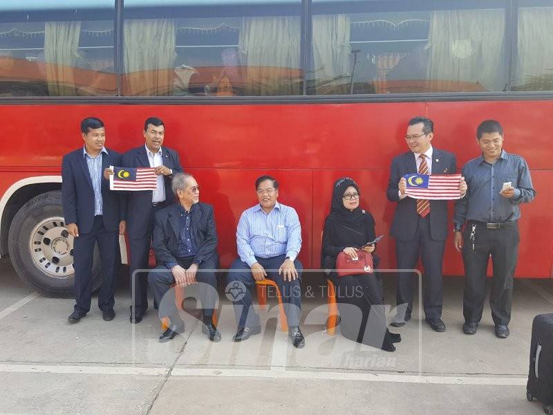 Othsman (duduk ditengah) bersama dengan Fatimah (duduk sebelah kiri) dan Wan Junidi (duduk sebelah kanan) serta Mustapha (berdiri sebelah kanan) sambil memegang bendera Malaysia menghantar rombongan rakyat Malaysia pulang di Lapangan Terbang Antarabangsa Siem Reap.