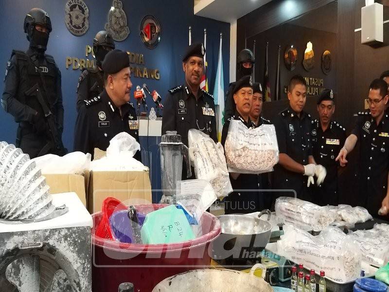 Mohmad (tengah) menunjukkan dadah dan peralatan memproses dadah yang dirampas.
