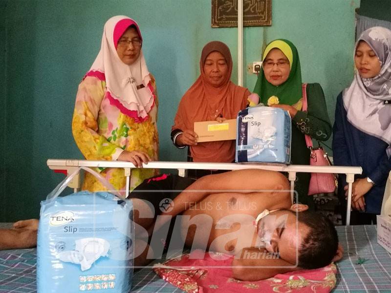 Zaini (kanan, dua) menyampaikan cek dan barangan keperluan kepada Zakiah, hari ini.