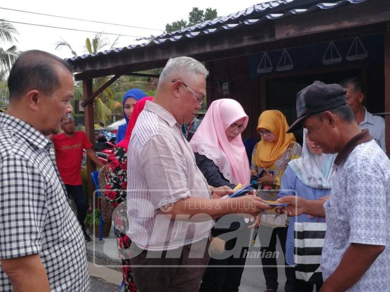 Noh (tengah) bersama pimpinan UMNO Bahagian Tanjong Karang menyampaikan sumbangan kepada mangsa ribut di Dewan Mutiara Kampung Seri Tiram Jaya.